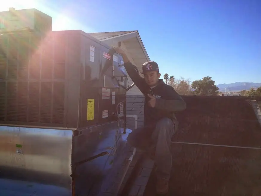 HVAC technician performing AC Tune-Up on a rooftop unit in Davie